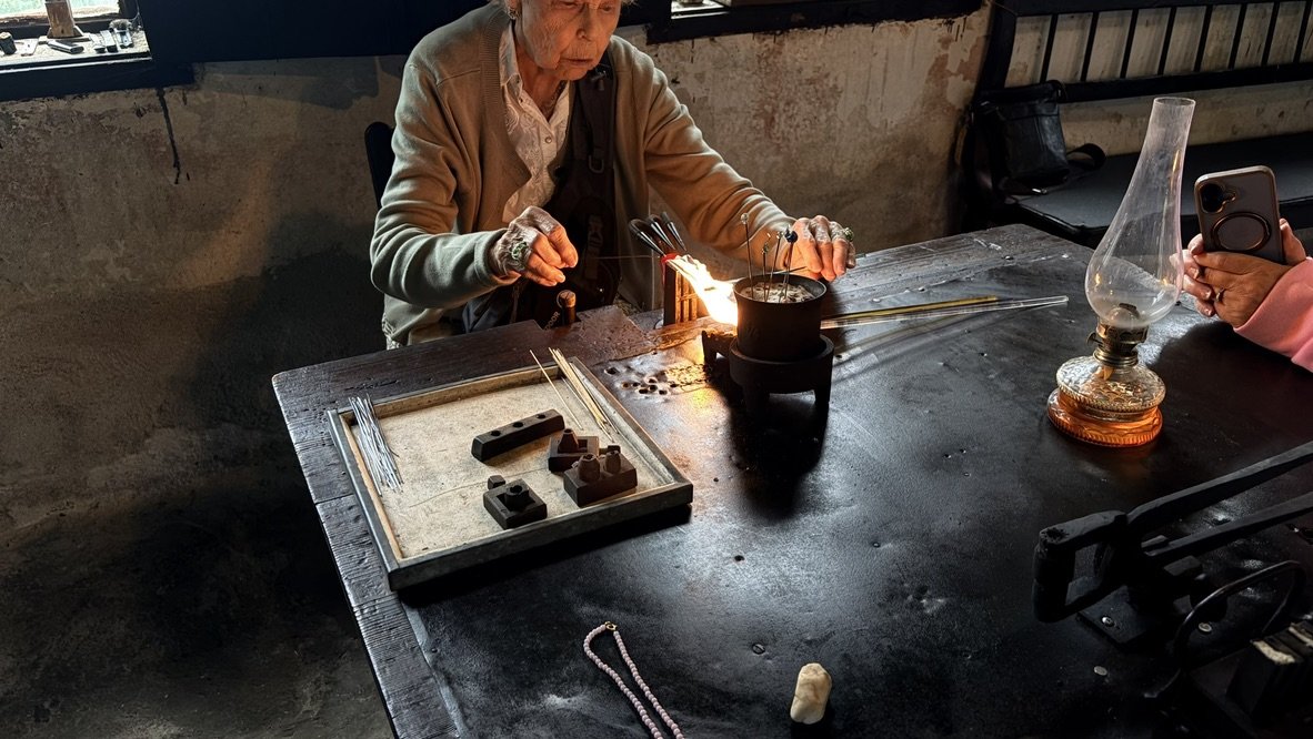Craftswoman lampworking glass beads at a traditional workshop bench