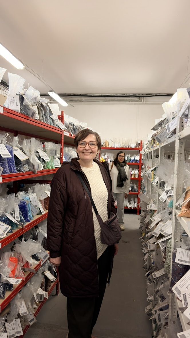 Shopper in a purple coat among the bead shelves