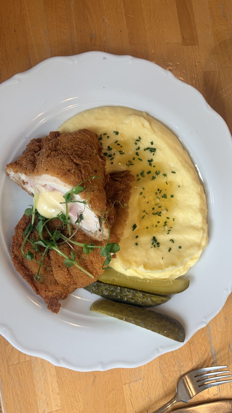 Cordon bleu – breaded schnitzel filled with ham and cheese – with creamy mashed potato and pickled gherkins