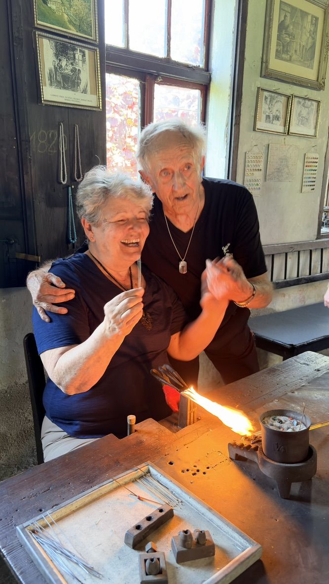 Two makers laughing while working at the torch